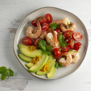 Orange Avocado Shrimp Salad on a plate with mint leaves.