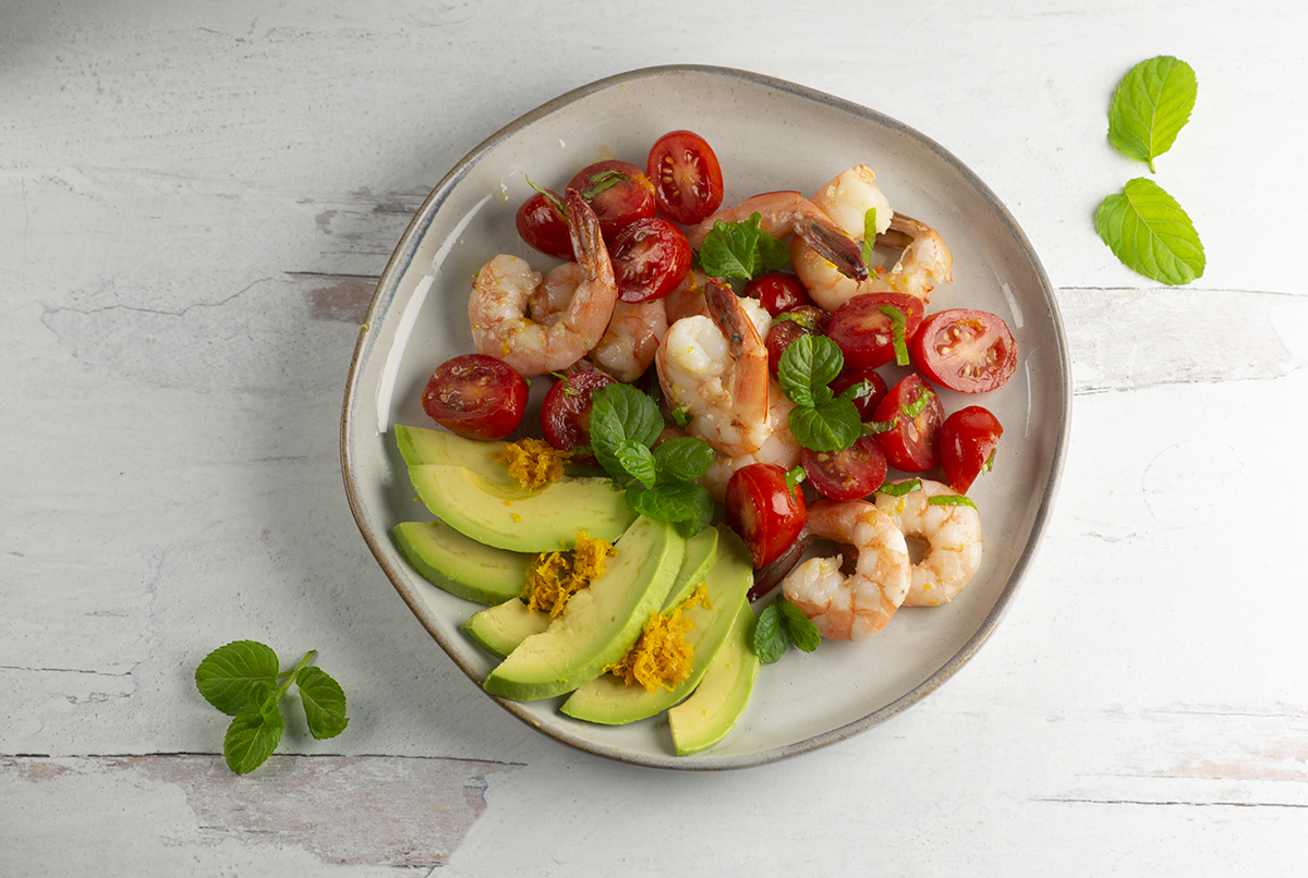 Orange Avocado Shrimp Salad on a plate with mint leaves.