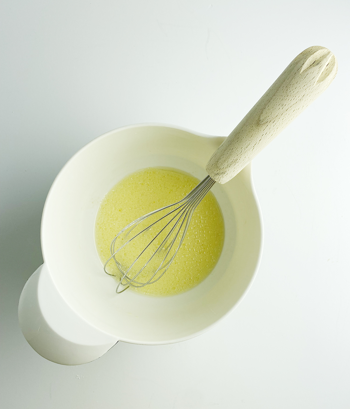 Egg and vegetable oil mixture in a mixing bowl.