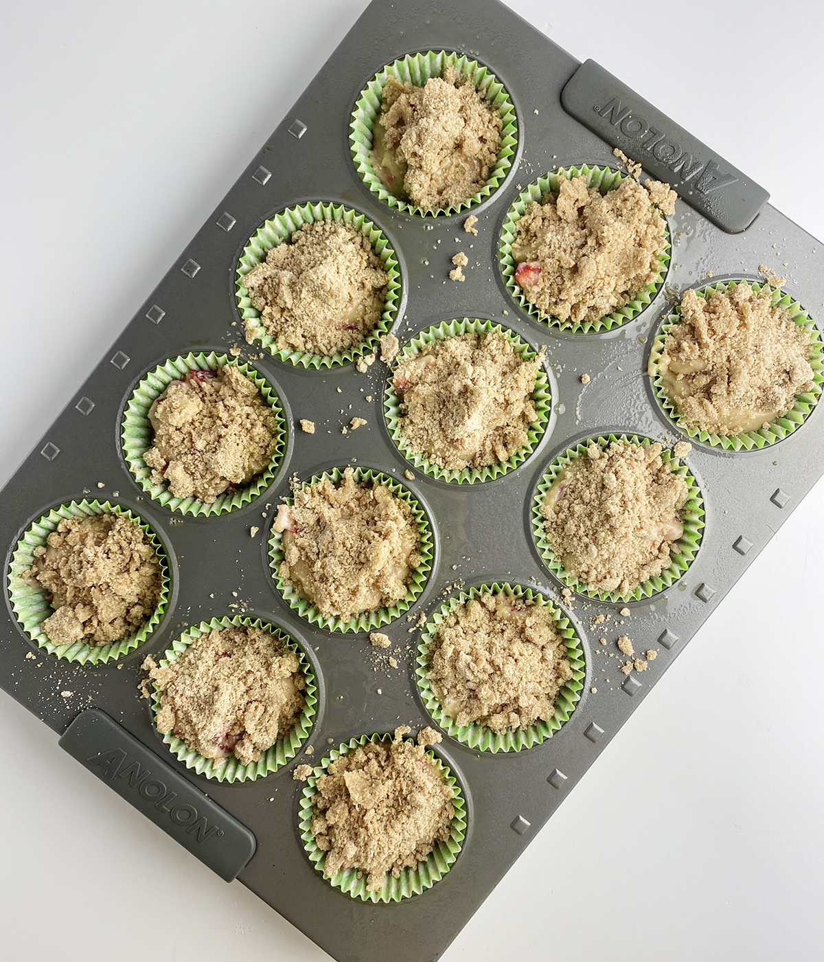 Strawberry crumble muffin batter in a muffin tin.