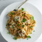Pasta with chicken parm meatballs on a plate with a fork.