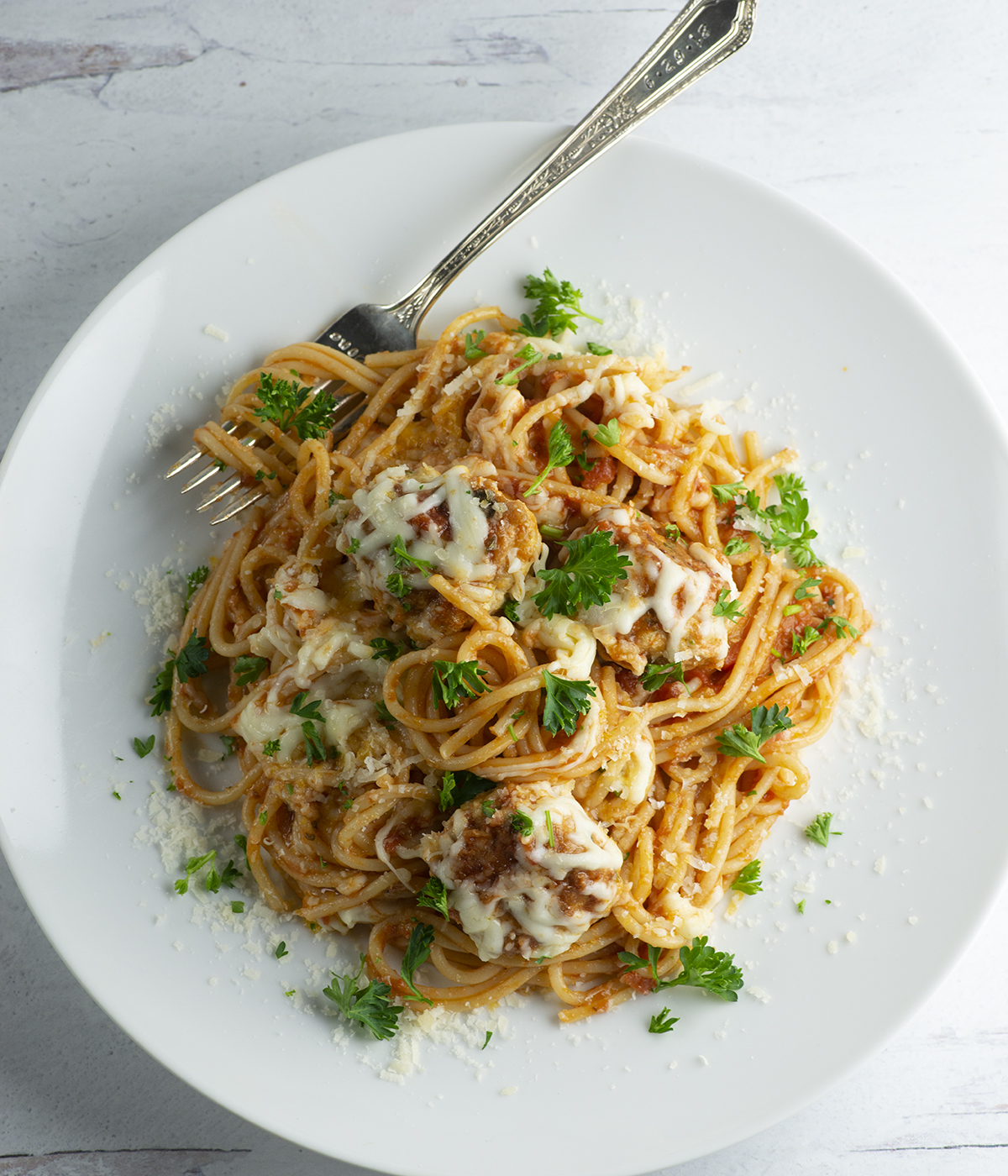 Pasta with chicken parm meatballs on a plate with a fork.