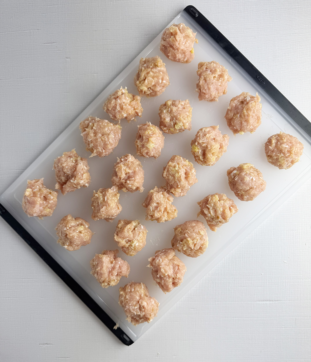 Uncooked Chicken meatballs on a cutting board.