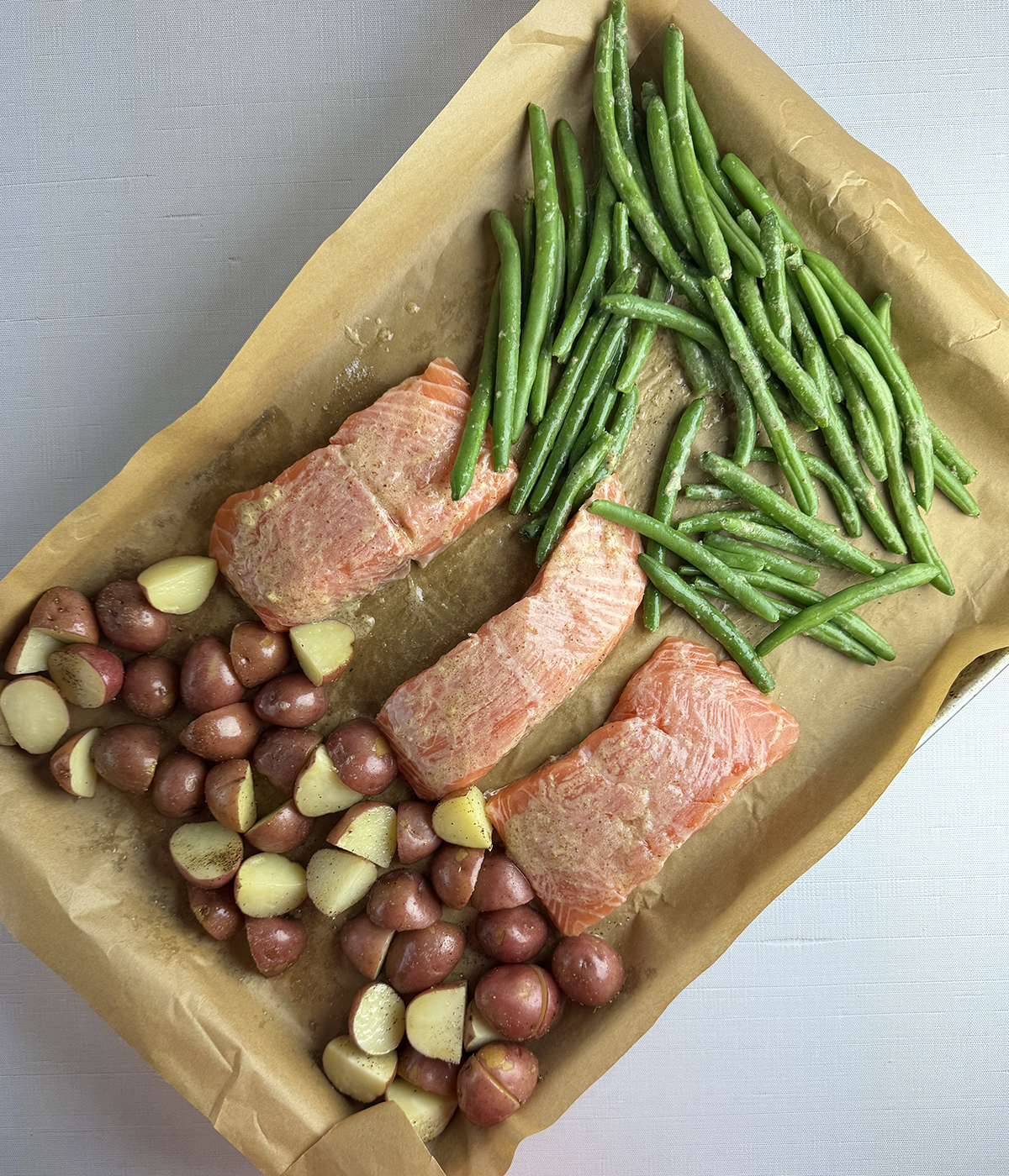 Salmon and vegetables on a baking sheet ready for the oven.