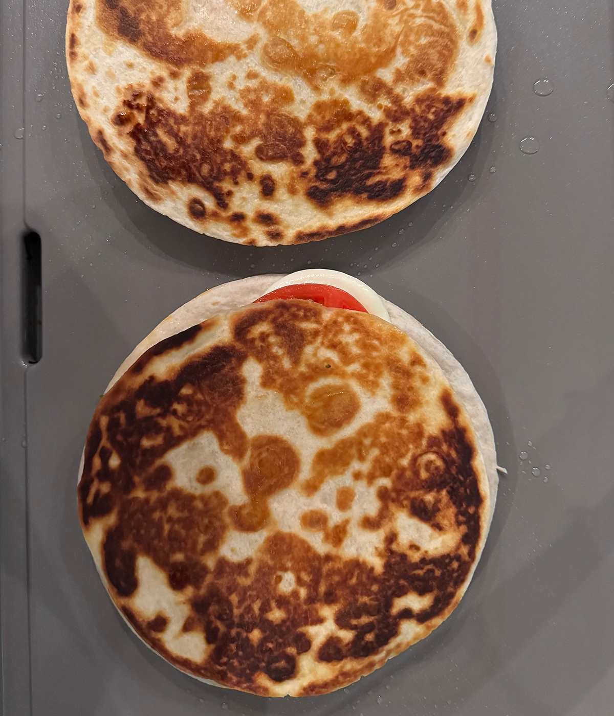 Browned caprese quesadilla on a griddle.