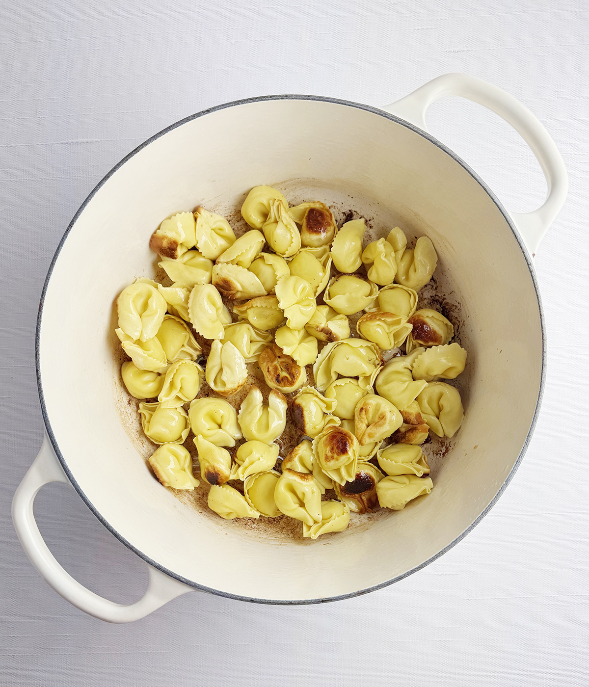 Browned tortellini in a pot.