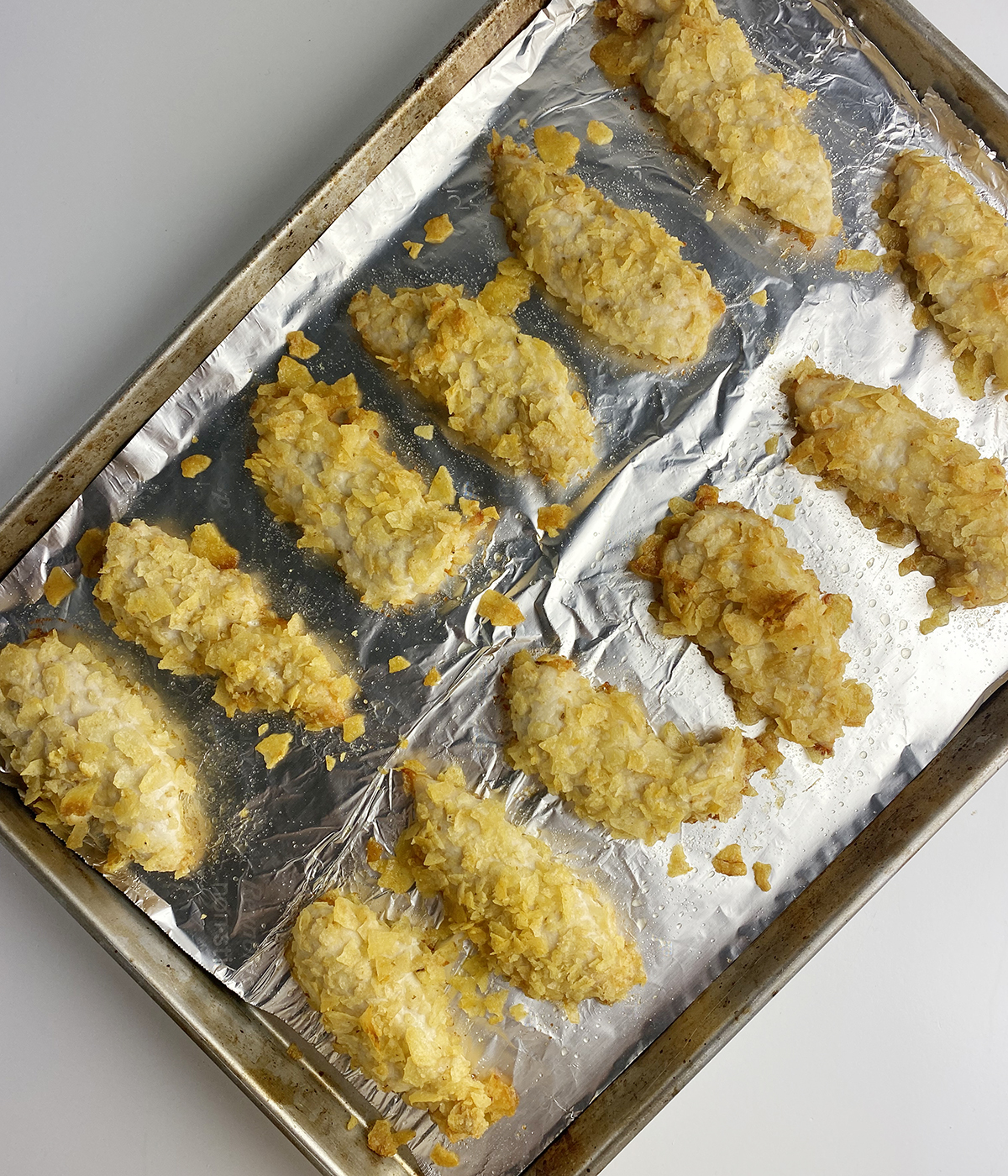 Baked chicken tenders on a baking sheet.