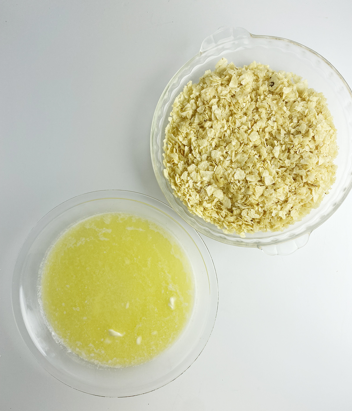 Crushed potato chips and melted butter in bowls.