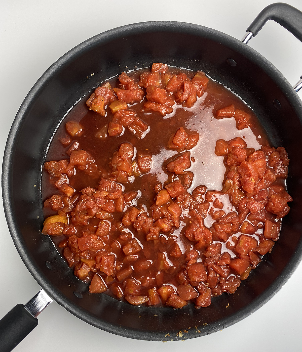 Wine and tomatoes simmering in a skillet.