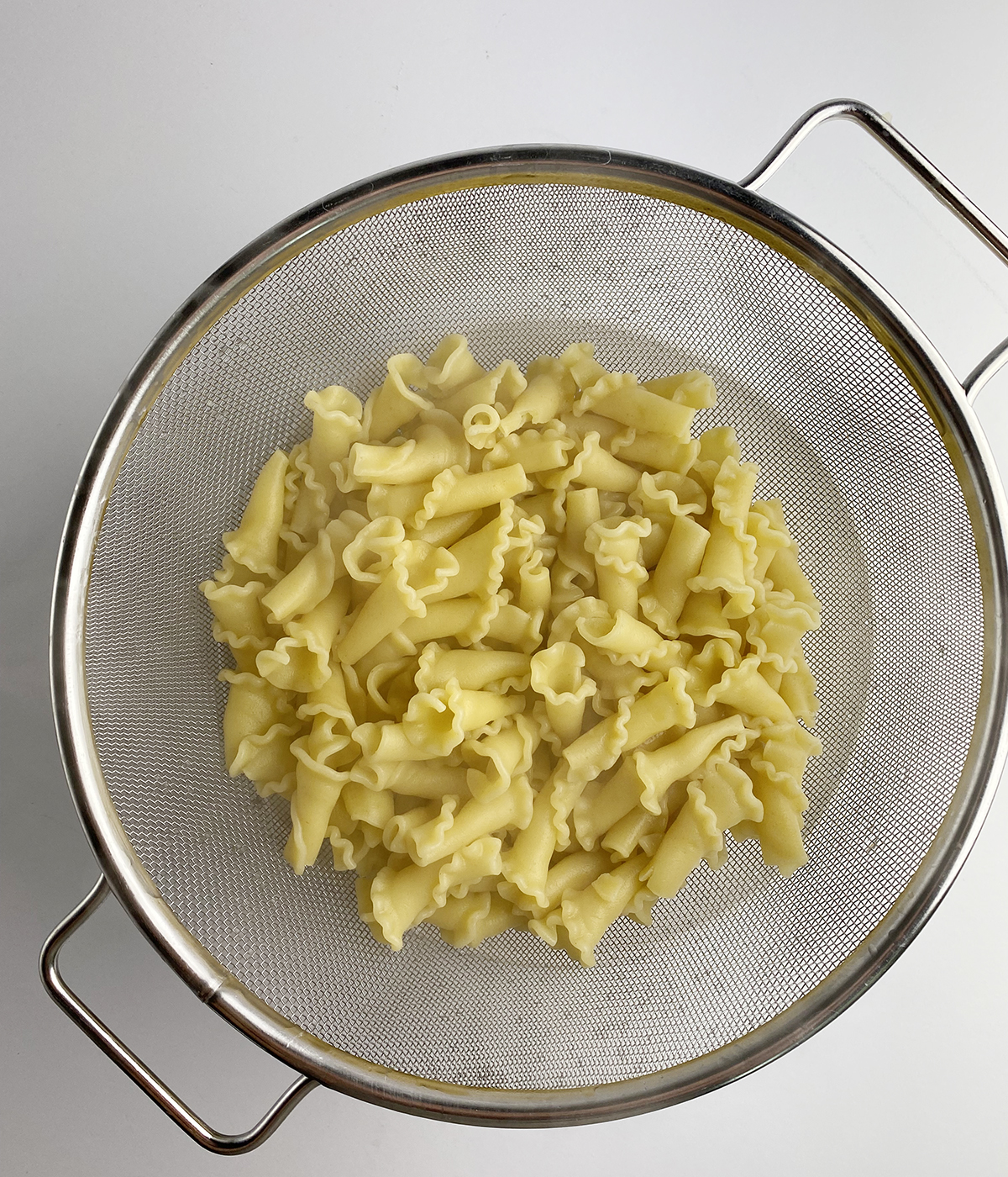 Pasta draining in a strainer.