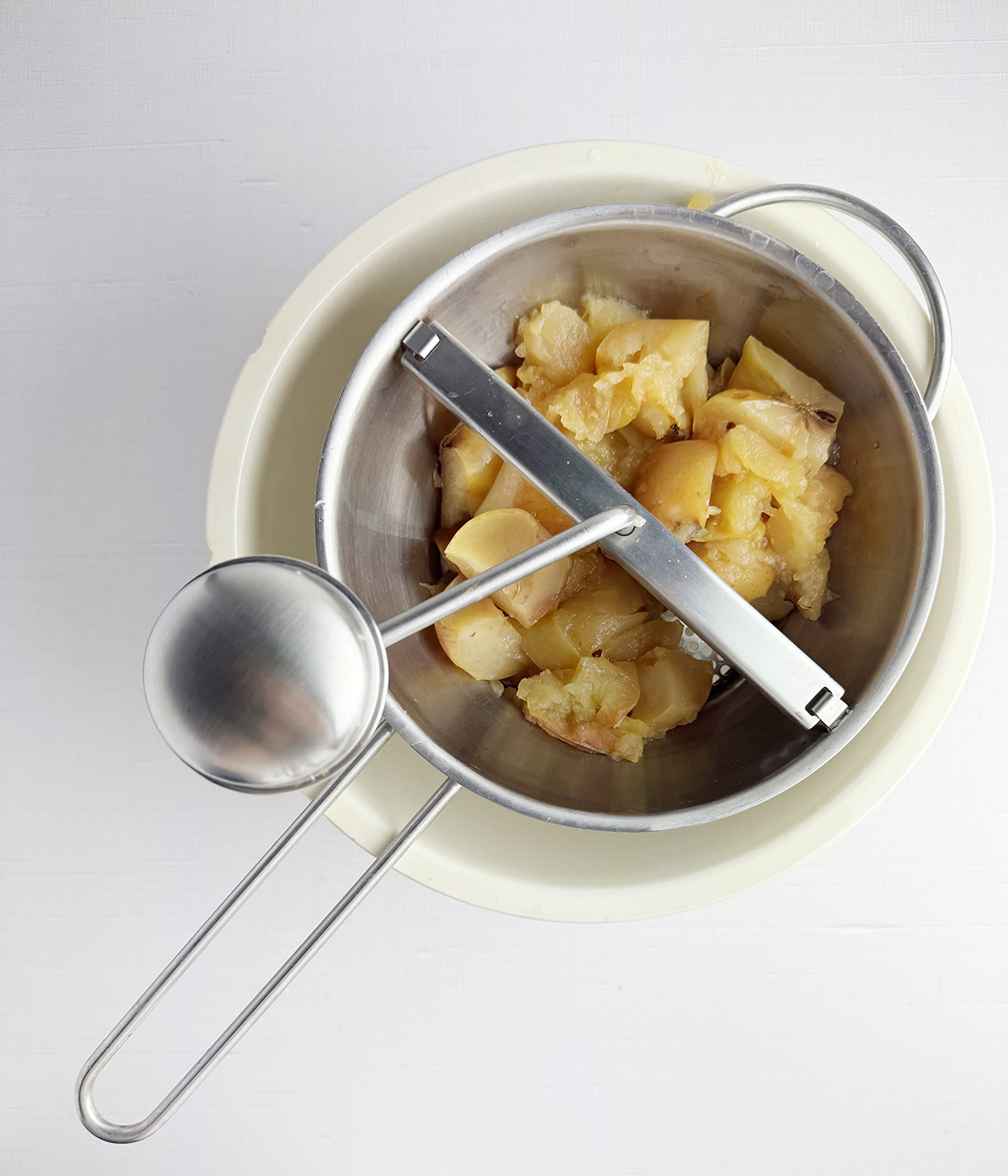 Cooked apples going through a food mill.