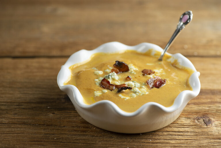 Pumpkin bacon soup in a bowl with a spoon.