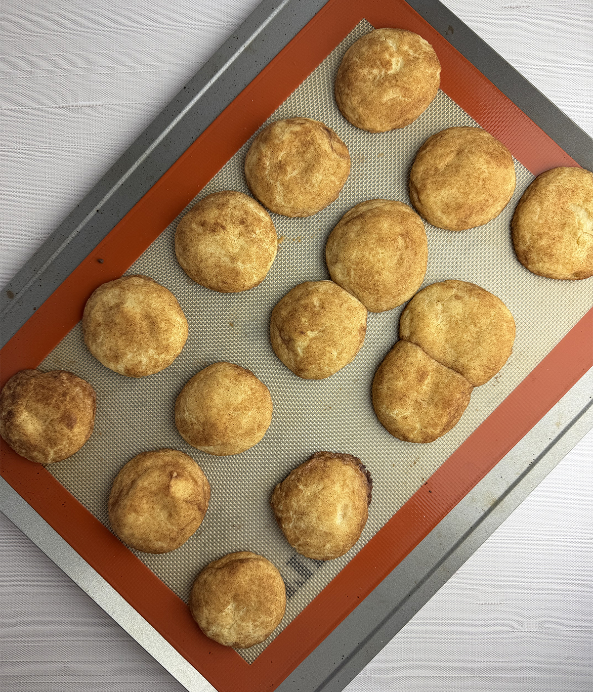 Baked snickerdoodle cookies on a baking sheet.