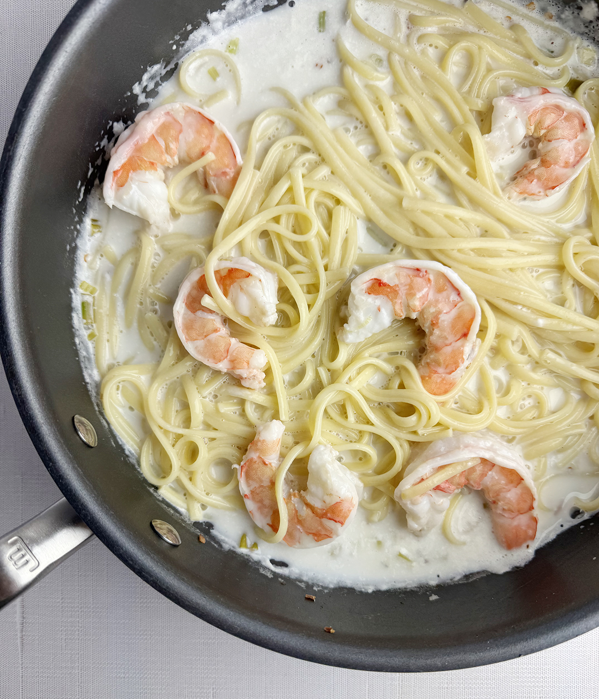 Pasta and shrimp in coconut sauce in a skillet.