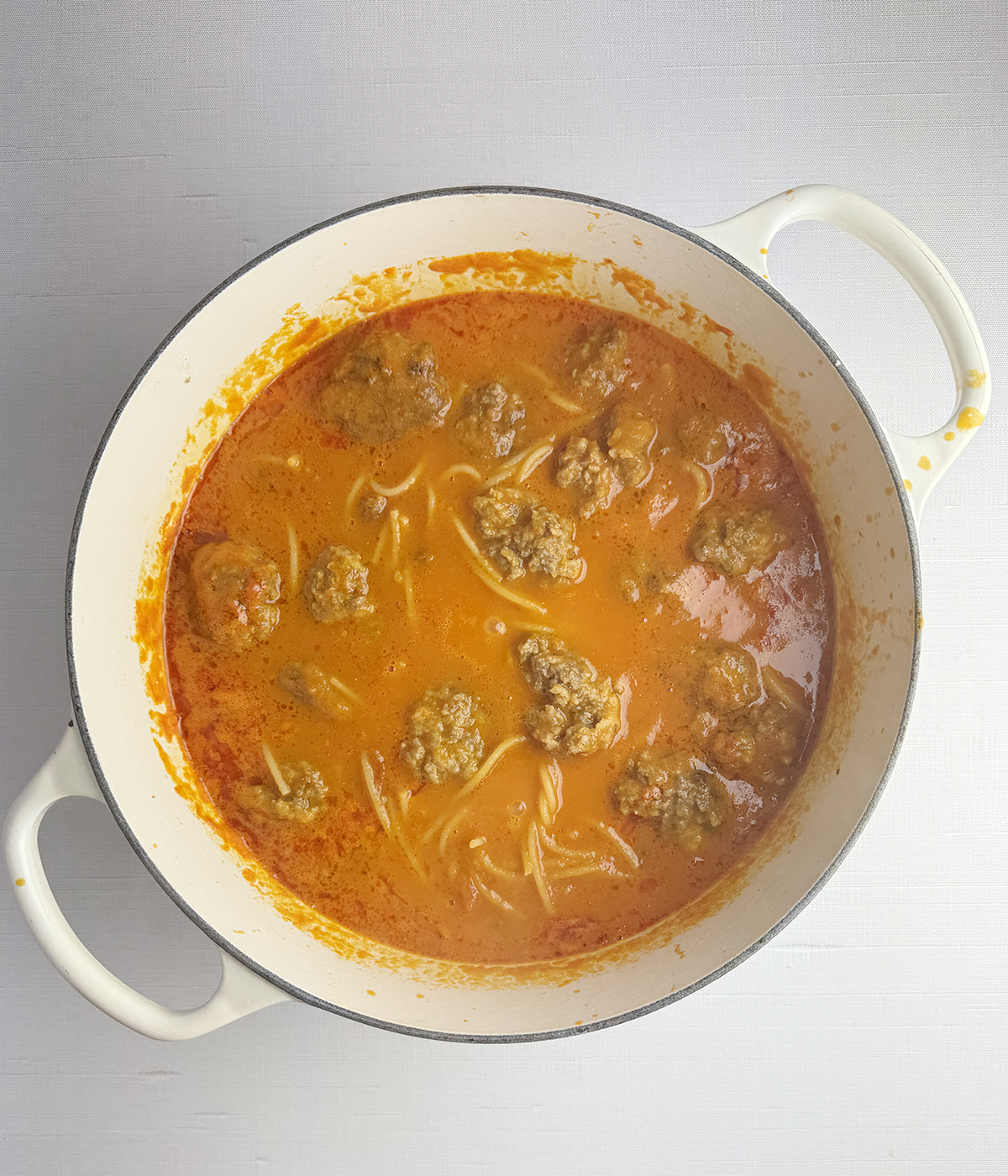 Spagehtti and meatballs cooking in a pot.