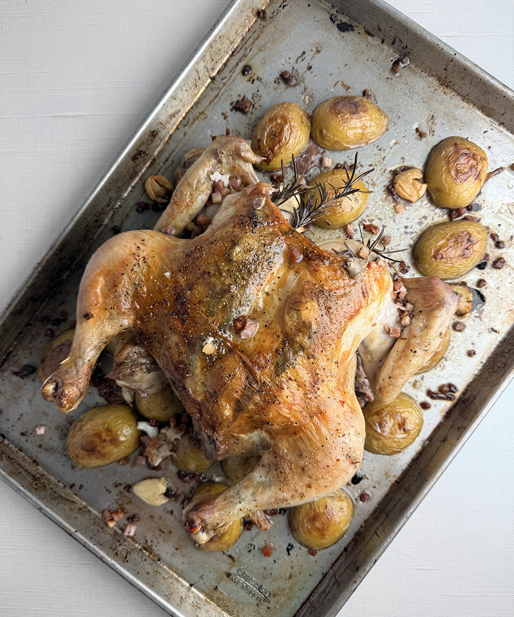 Cooked spatchcock chicken on a baking pan.