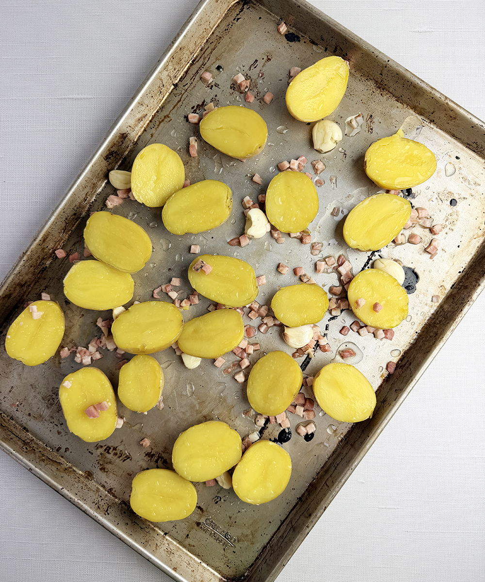 Potatoes and pancetta on a baking pan.