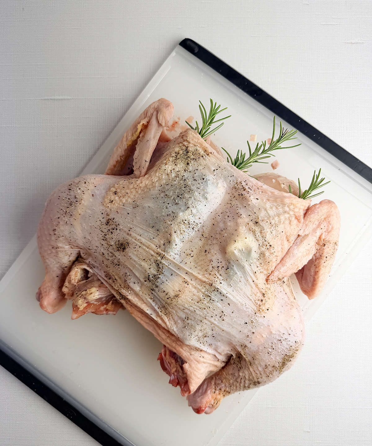 Spatchcock chicken with herbs on a cutting board.