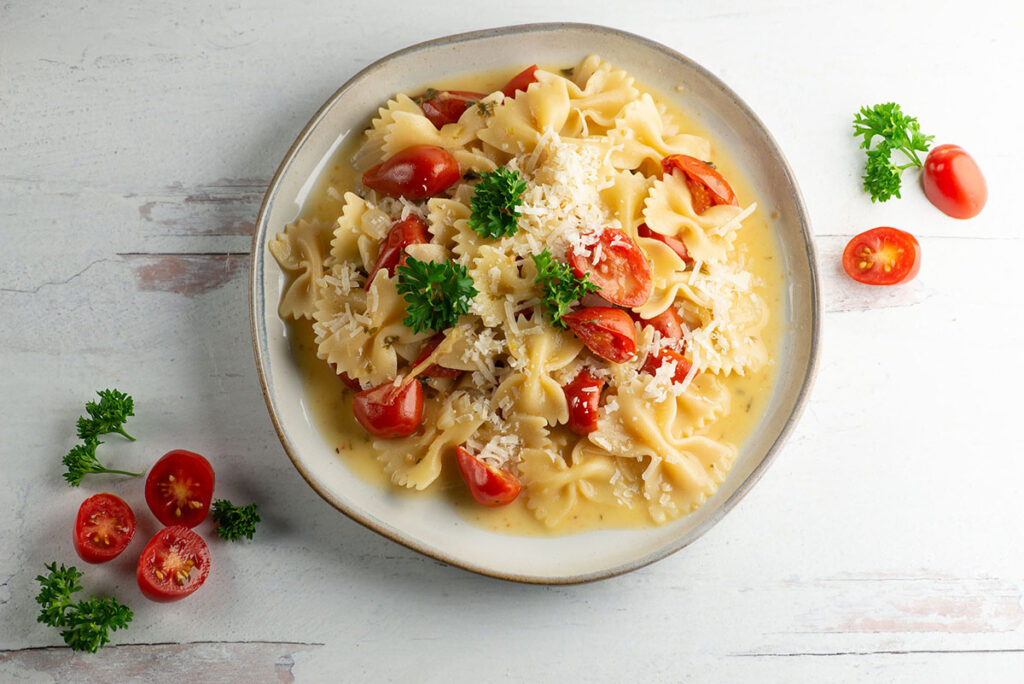 Tomato parmesan pasta on a plate with cherry tomatoes.