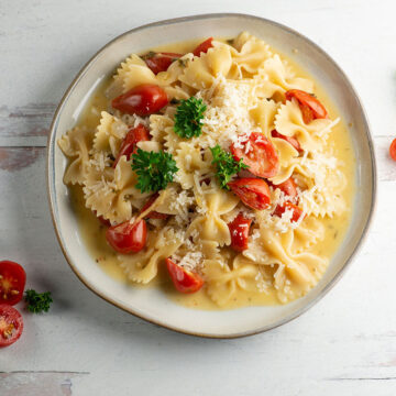 Tomato parmesan pasta on a plate with cherry tomatoes.