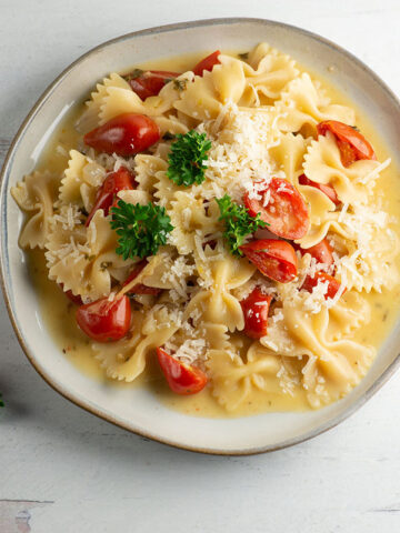 Tomato parmesan pasta on a plate with cherry tomatoes.