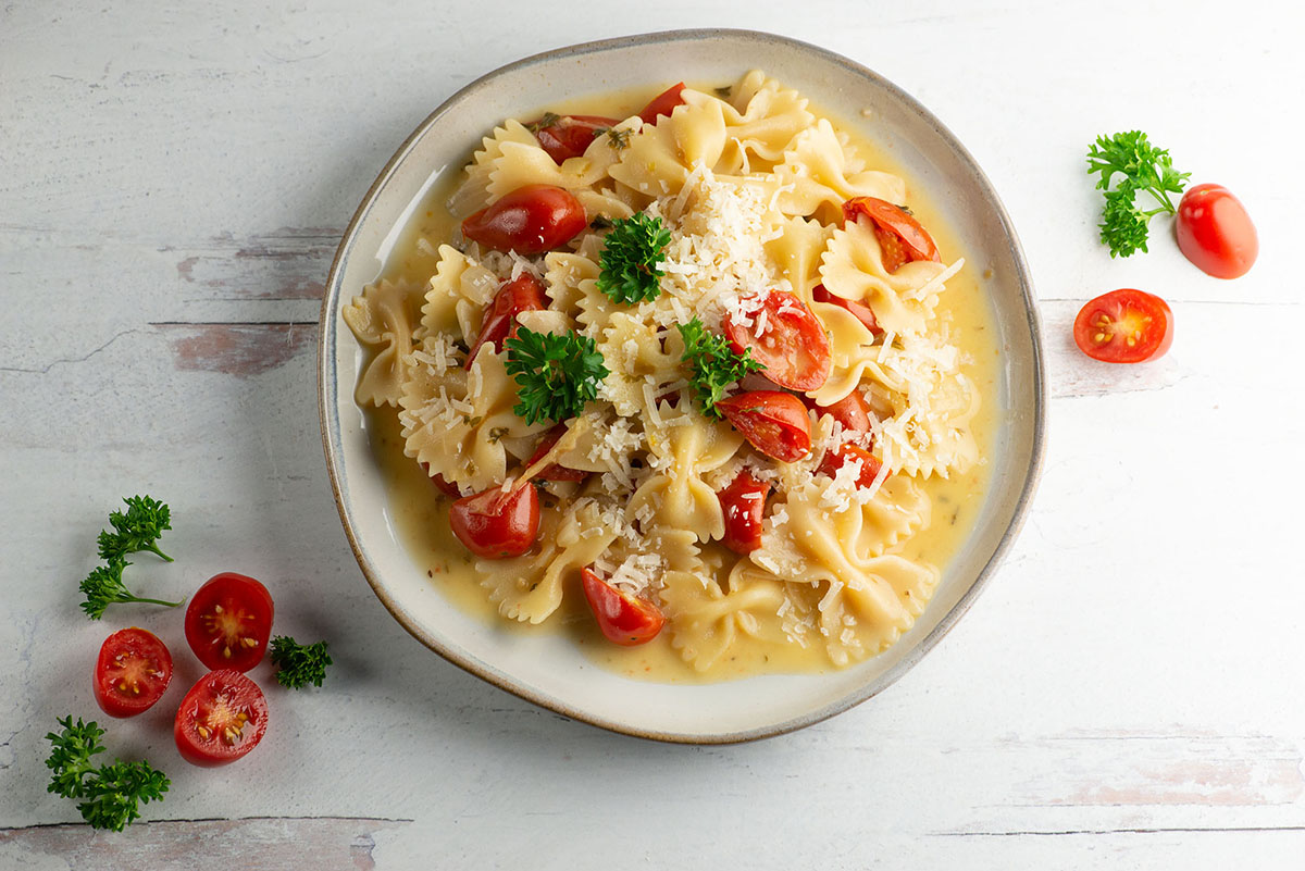 Tomato parmesan pasta on a plate with cherry tomatoes.