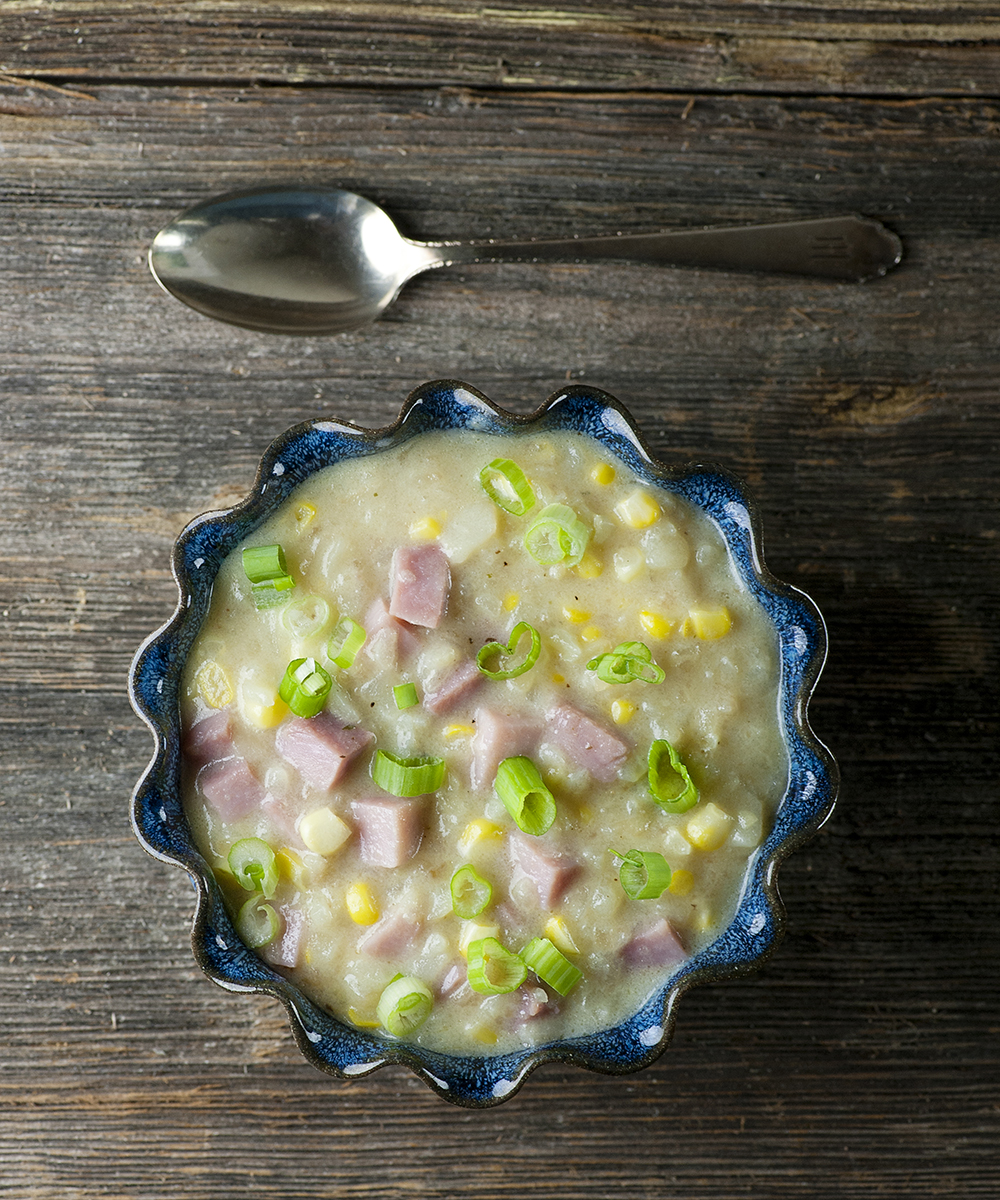 Ham potato chowder in a bowl with a spoon.