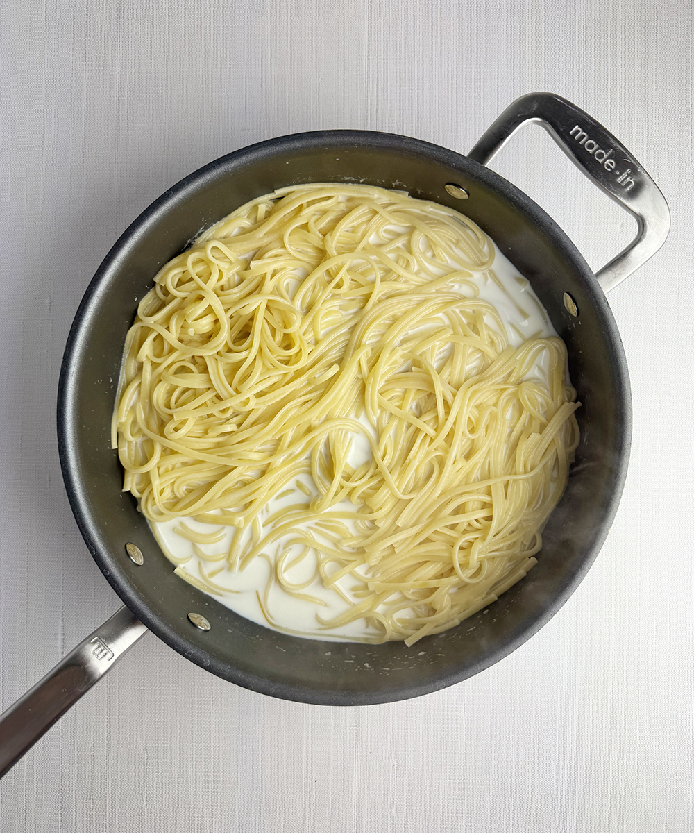 Pasta and cream in a skillet.