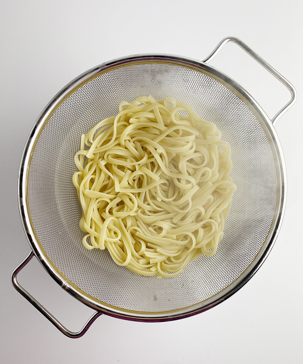 Pasta draining in a strainer.