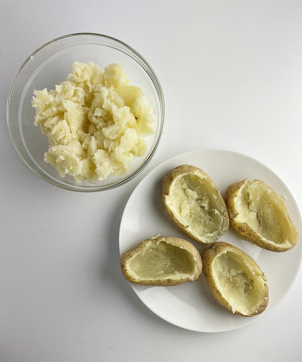 Potato skins with potato scooped out and in a bowl.